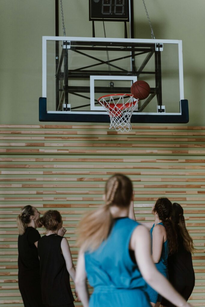 A group of women playing basketball in an indoor court, focused on the hoop.